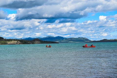 2 canoes with paddlers on a big lake with mountains